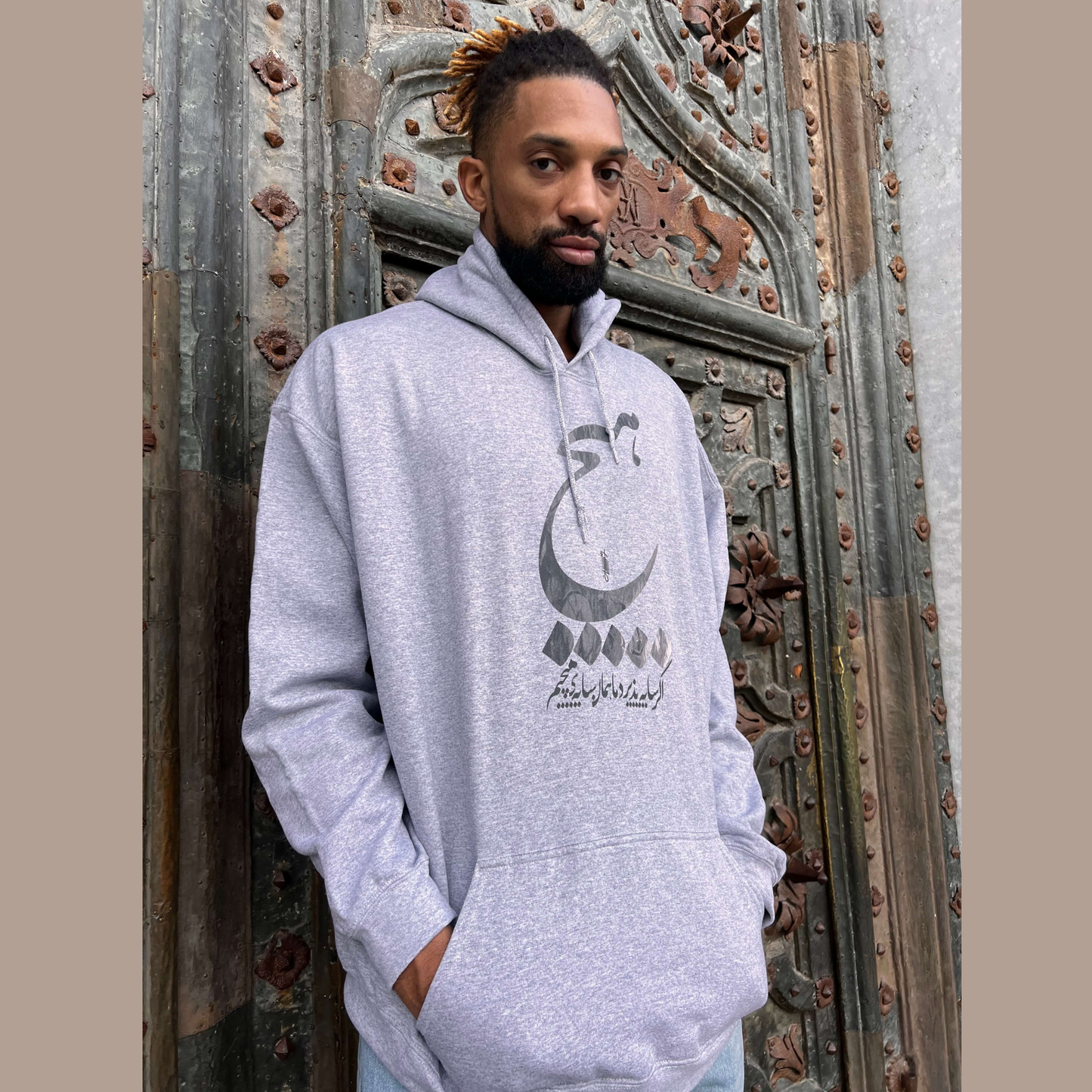 Unisex Persian calligraphy hoodie with ‘Hich’ design wearing by khem birch– gray Farsi sweatshirt, cultural streetwear gift idea, stylish fashion for USA and Canada shoppers.