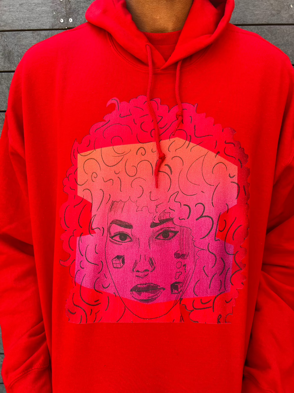 Red unisex hoodie with bold curly-haired face art print – abstract afro female portrait in pink tones, streetwear style