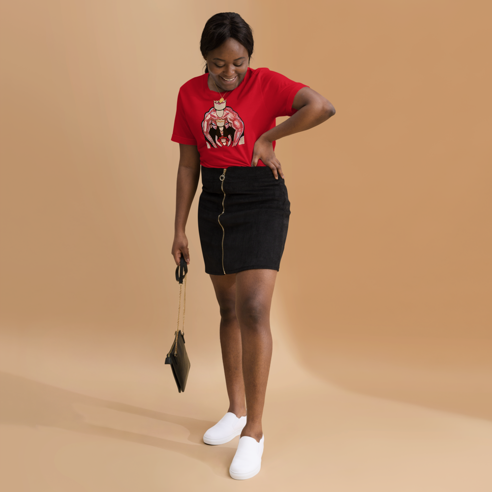 Red t-shirt with a striking graphic design featuring a muscular king and queen in a powerful embrace, displayed on a light wooden background with festive decorations and gift boxes.