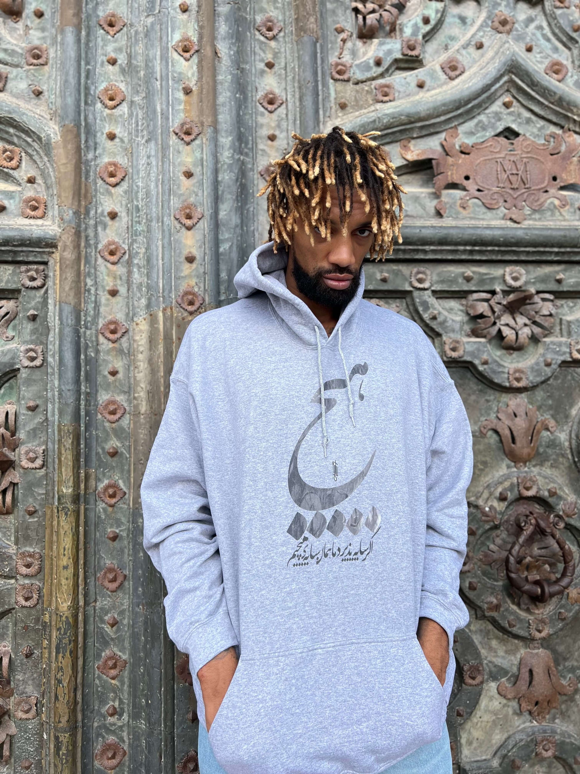 Khem Birch wearing Textured hoodie featuring Persian calligraphy and meaningful verse.